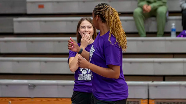 Two MGA women's basketball players smile during warm ups